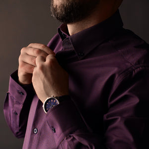 a man in a purple shirt adjusting his watch