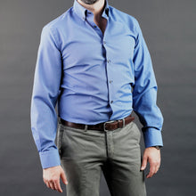 a man in a blue shirt and tie posing for a picture