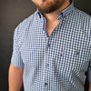 a man with a beard wearing a blue and white checkered shirt