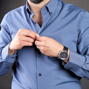 a man in a blue shirt adjusting his watch
