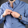 a man in a blue shirt adjusting his watch